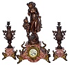 French marble and cast metal garniture set: 8 days, time and strike, clock with figures titled "Retour Du Bois"; two urn candlestick sidepieces, c1880