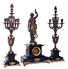 Rare French mystery clock by Guilmet, black slate with gilt and patinated ornament, with candelabra garniture, the signed time and strike, movement with crank and stirrup escapement, a bronzed spelter figure of a woman on top of the case, holding the pendulum, the pendulum impulsed through the nearly imperceptible movement of the gilt base on which the figure stands, candelabra in patinated spelter with Classically inspired ornament, on black slate bases matching the clock, later glass dial with black painted Roman numerals allowing the action of the movement to be observed, the original black slate dial with gilt Roman numerals is included with the clock, gilt bezel with thick beveled glass, gilt steel hands, pendulum with glass center, c1875