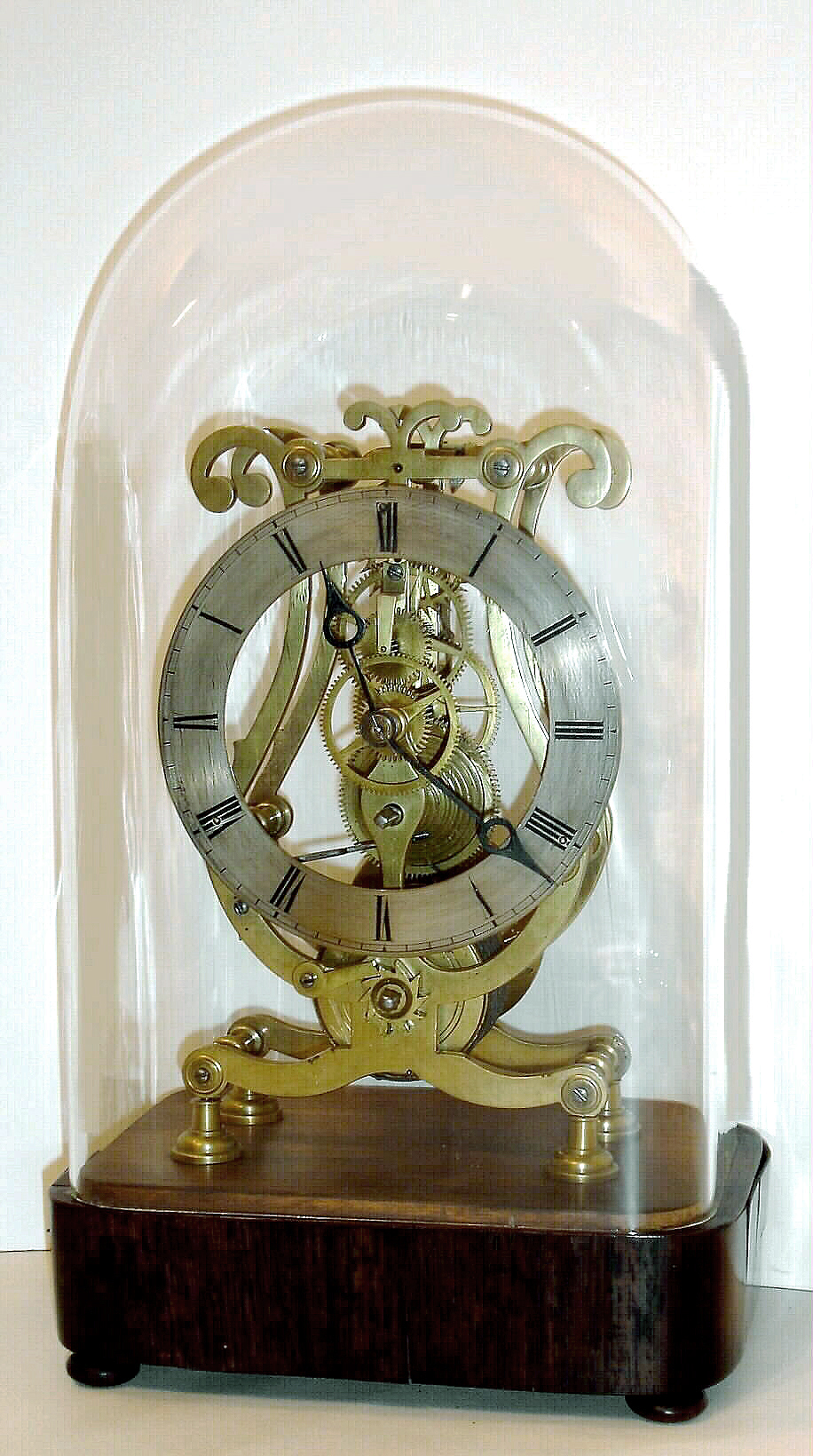 English, a single fusee skeleton timepiece, with a simple solid brass chapter ring, in a "Lyre" style frame, and with robust baluster pillars, on a rosewood veneered base with glass dome, c1860 — Antique Clocks Price Guide