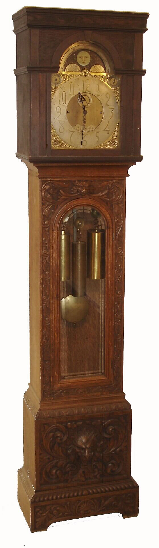 English tall clock presented "THE ASSOCIATION OF DIAMOND MERCHANTS, JEWELERS &amp; SILVERSMITHS, 6 GRAND HOTEL BUILDINGS, TRAFALGAR SQUARE, LONDON", 8 days, time and Whittington chime on 8 bells or your choice of Westminster on 4 large flat wire gongs, and striking the hours on a still larger deep toned gong.  Brass three weight driven movement in an a heavily carved English oak case. The brass dial has silvered chapter ring, tune and silent selection dials, moon phase and brass corner spandrels, c1890 — Antique Clocks Price Guide