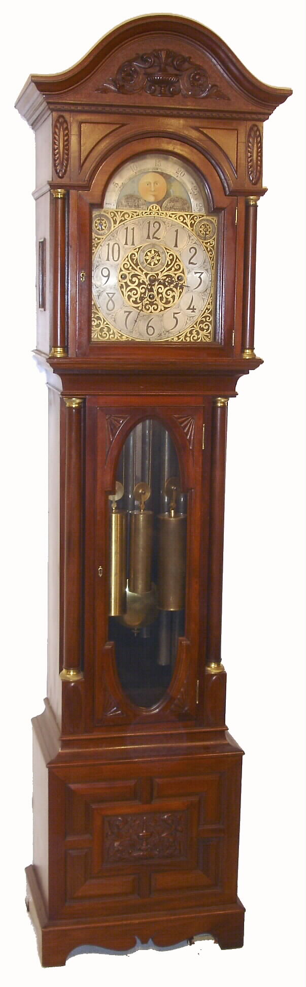 English tall clock, 8 days, time, strike and chime on 9 tubes playing two tunes, Westminster or Whittington, three brass weight driven movement in a cherry and veneer case with carved urn and paneled plinth, carved arch top and full columns with brass capitals flanking hood door. The brass dial has moon phase, silvered chapter ring, silence and tune selection dials, c1900 — Antique Clocks Price Guide