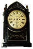 English, twin fusee, bell strike bracket clock, Regency period, ebonized veneer with brass inlay, and a painted enamel dial bearing the name Dewhurst, in Clitheroe. The Gothic style case with cast brass side frets and pineapple finials, c1820