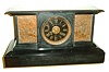 French, for Henry Semkem, Washington, black slate mantel clock, the front with incised line decoration, patinated bronze panels with Roman soldiers on horseback, some carrying severed heads on pikes, the left panel marked "Imperator" below their commander, patinated bezel with beveled glass, Roman numeral black slate dial, gilt hands, 8 days, time and strike, movement, c1880
