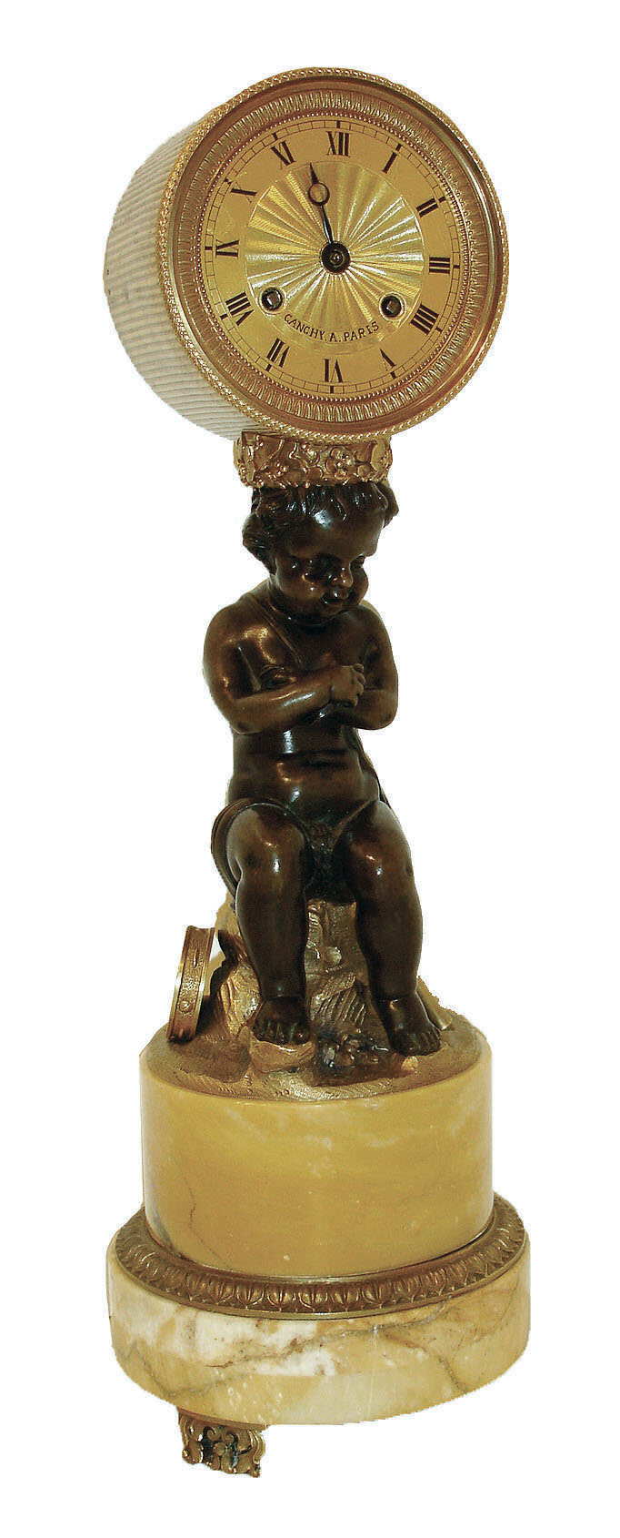 France, figural mantel clock, round siena marble base, gilt feet with foliate ornament, patinated putto with arms crossed, seated on a stump and with tambourine and pipes at his feet, the drum form clock case balanced on a wreath atop his head, Roman numeral gilt metal dial with engine turned center, 8 days, time and strike, pendule a Paris movement marked "Canchy", pinwheel escapement with escape wheel and pallets planted outside back plate, silk suspension, c1840 — Antique Clocks Price Guide