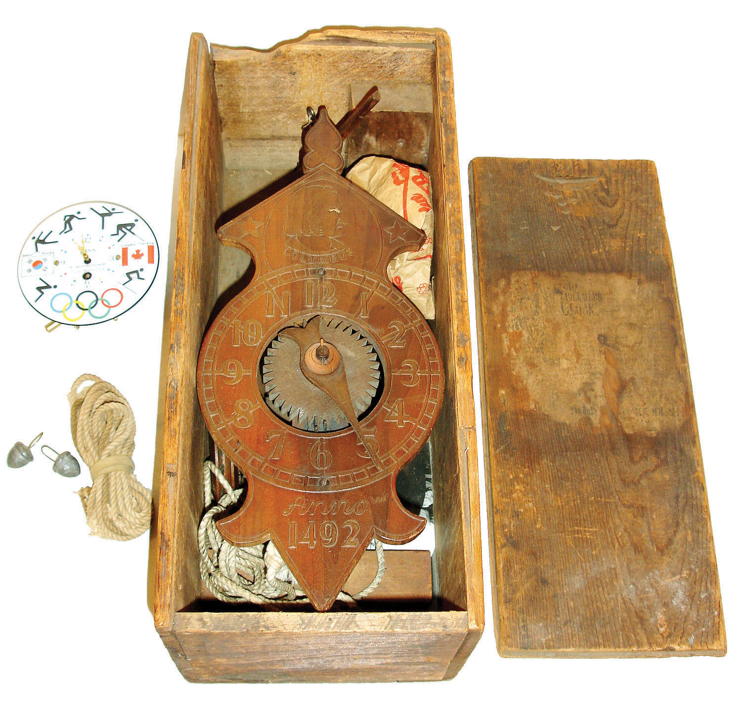 Clocks- 2 (Two): (1) Wooden works weight driven, foliot escapement timepiece, sold as a souvenir at the Columbian Exposition, Chicago, which began in 1892. The clock front is embossed with a dial, a bust of Columbus and his name at top, and the year 1492 at bottom. This clock comes complete with its original wooden shipping box, with label, C.1892, (2) a German 30 hours, pendulette souvenir clock from the 1988 Winter Olympics,. — Antique Clocks Price Guide