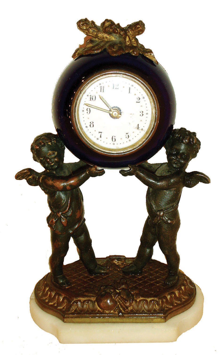 Germany, 30 hours, time only, small desk or nightstand clock, Cobalt blue ceramic case supported by two putti on a gilt and marble base surmounted by a trophy consisting of a quiver, wreath, and torch, Arabic numeral white enamel dial, luminous hands, c1910 — Antique Clocks Price Guide
