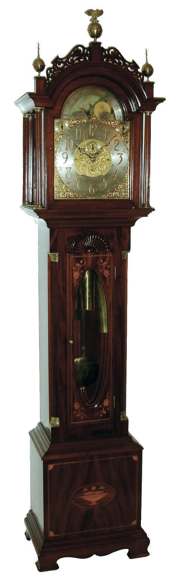 John Elliott, London, England for Bigelow, Kennard &amp; Co., Boston, Mass., tall clock, time, strike and Westminster chime on cathedral gongs,  8 days, three brass weight driven movement in a mahogany inlaid case with floral motif on door and urn with flowers on base, both framed with herring bone inlay, Roxbury fretwork and brass capped full Corinthian columns on hood, three upper brass finials including center eagle finial, trunk door surmounted by clamshell carving and flanked by fluted quarter columns with brass caps and bases, all resting on a cutout skirt with ogee bracket feet.  The brass dial has ornately cutout and engraved brass corner spandrels and profusely engraved dial center silvered chapter ring with applied brass numerals, hour strike / silent and Westminster chime / silent selectors and moon phase dial, c1910 — Antique Clocks Price Guide