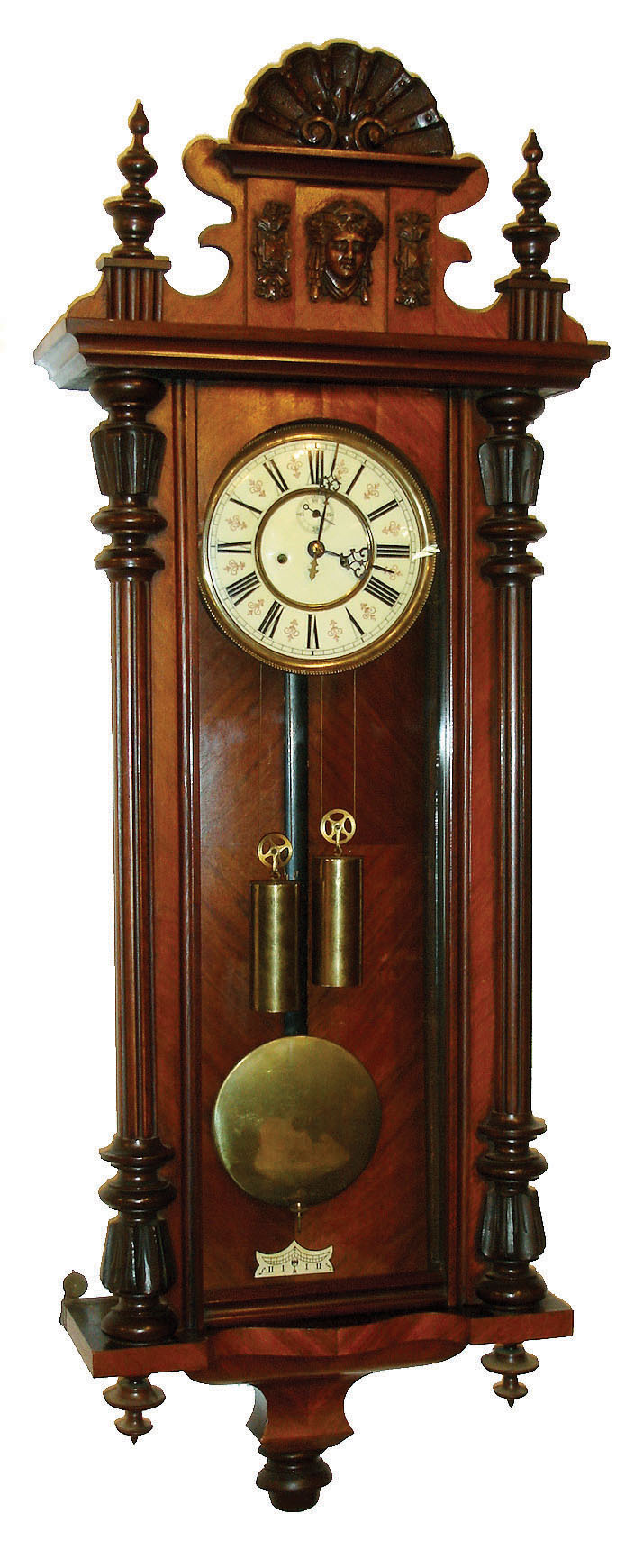 Gustav Becker, Freiburg, Germany, Vienna regulator, walnut veneered case with finials, removable crest with composition mask and scallop shell, Roman numeral white enamel dial with small seconds below 12:00, pierced blued steel hands, brass 8 day weight driven time and strike movement, brass weights, c1900 — Antique Clocks Price Guide