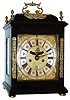 Early English bracket clock, ebony veneered oak case with domed top, glazed sides and back, and with decorative cast mounts, all resting on turned brass feet, Roman numeral composite dial with winged cherub spandrels, silvered chapter ring, matted and engraved center, aperture above center arbor displaying mock pendulum, and with date display below, blued steel hands, 8 days, time and strike, 6 pillar fusee movement with verge escapement and engraved back plate, back cock mounted with large ornamental cast plate, originally fitted with Dutch striking, now removed, as currently configured striking the hours on a bell, the rack fitted between the plates and gathered by a pallet fitted to the third wheel arbor, c1700
