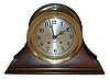 Chelsea Clock Co., Chelsea, Mass. 6" ships bell clock in a cast brass case, Arabic numeral silvered dial moon style hands, and with mahogany base, c1980