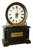 Hamburg American Clock Co., Germany, "La Mysterieuse", desk clock with transparent dial, and no apparent connection to the movement, ebonized wooden case with engraved plaque, Roman numeral see through dial mounted in a molded brass bezel, blued steel Breguet style hands, 30 hour lever movement concealed in the clock base, c1920