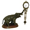 Junghans, Germany, elephant model swinging clock, patinated figure of an elephant mounted to a molded beechwood base, holding the 8 day swinging timepiece aloft at the end of his trunk, clock case with gilt and patinated surfaces, Arabic numeral white enamel dial signed "Junghans Germany" below 6:00, blued steel hands, 8 day time only, movement, c1920
