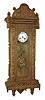 Tramp art clock case with spring Vienna movement, the case composed of chip carved and pierced graduated blocks stacked to create a very busy 3 dimensional effect, backboard with inlaid vine with flowers, case sides with decorative frosted glass panels, Roman numeral white enamel dial with illegible signature, brass 8 days, time and strike, movement, and brass and steel gridiron style pendulum in the Art Nouveau style, c1930