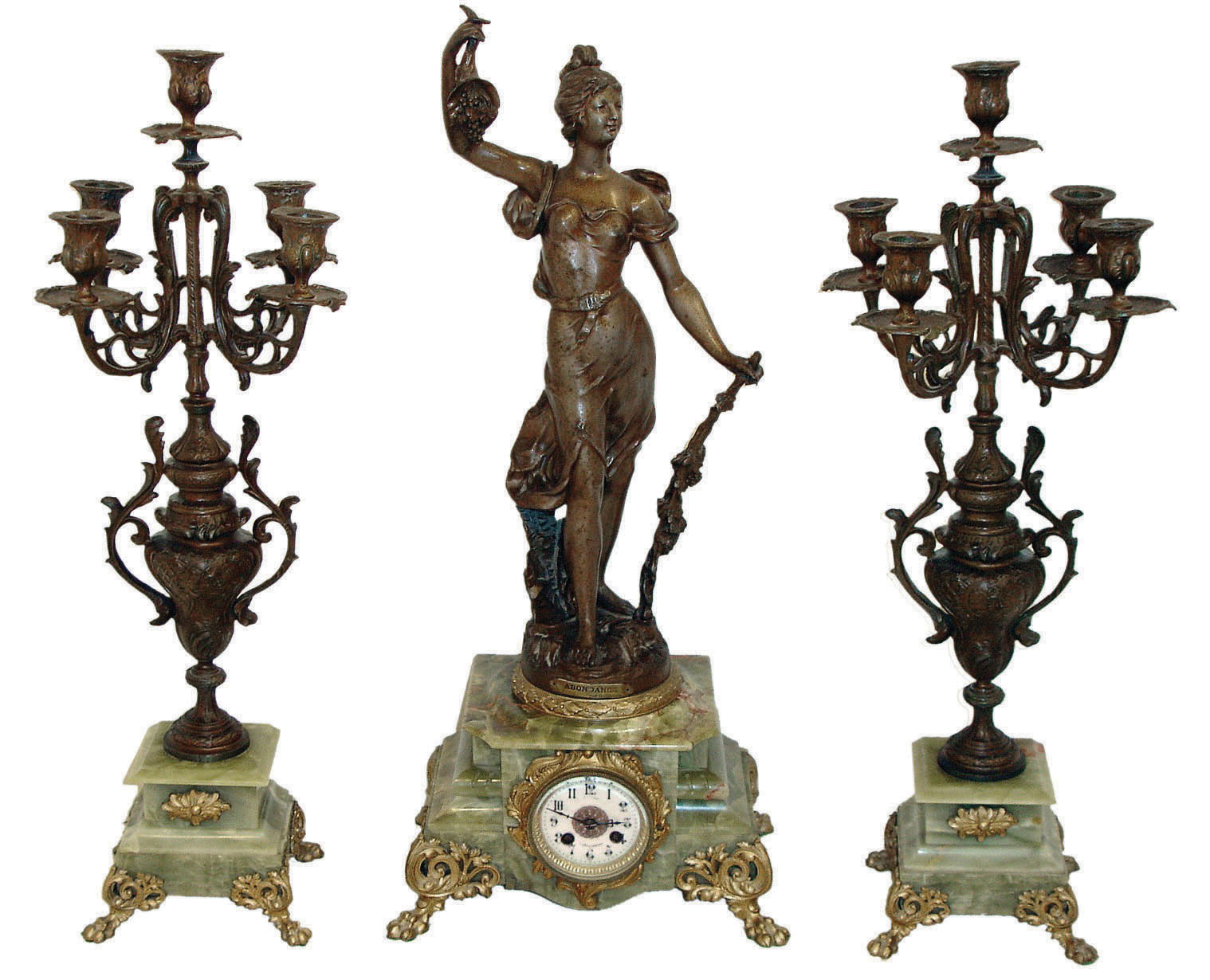 Clocks- 2 (Two): (1) France, large and impressive 3 piece figural mantel garniture, the clock case of green onyx on gilt leaf and scroll ornamented paw feet, gilt dial surround in the rococo style, surmounted by a patinated spelter female figure representing Abundance, the front of the sculpture with applied plaque reading ÓAbondance par GuilleminÒ, the sculpture also signed ÓL. GuilleminÒ, gilt bezel with beveled glass, Arabic numeral white enamel dial with illegible signature, blued steel hands, 8 days, time and strike, pendule a Paris movement marked Vincenti, the companion candelabras with patinated surfaces and racially ornament, resting on green onyx bases and also with gilt paw feet, c1890; (2) Painted metal figural Ansonia rear-wind, 30 hours, clock, c1885 with later adaption to an electric lamp with 1920Õs style shade. — Antique Clocks Price Guide