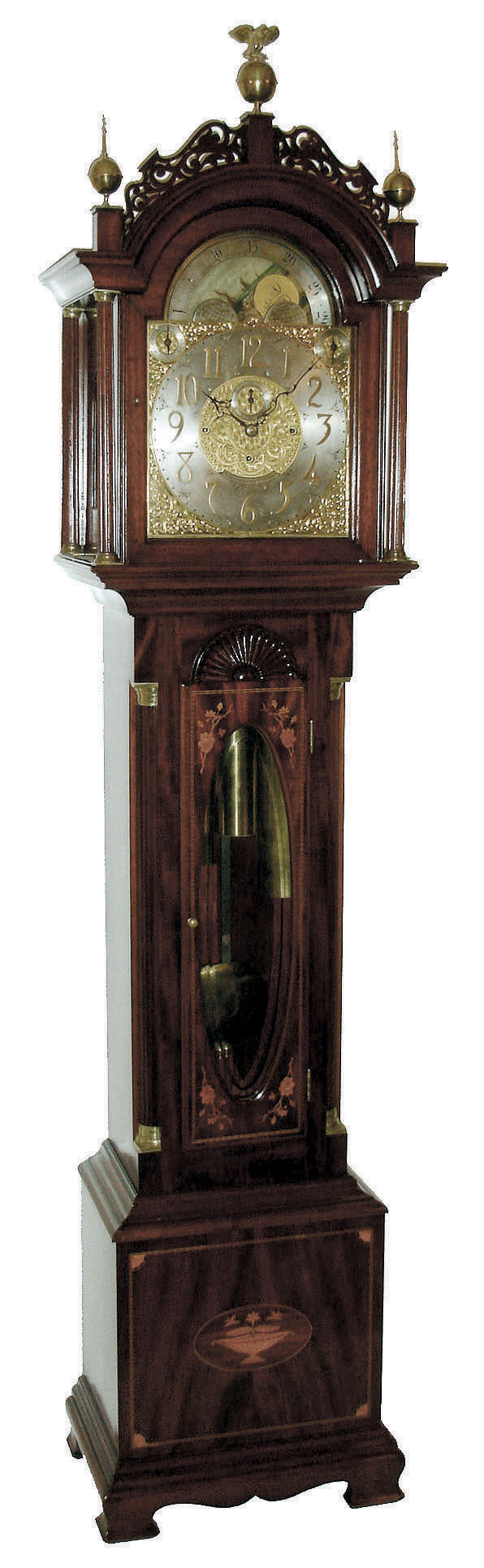 John Elliott, London, England for Bigelow, Kennard &amp; Co., Boston, Mass., tall clock, time, strike and Westminster chime on cathedral gongs, 8 days, three brass, weight driven movement in a mahogany inlaid case with floral motif on door and urn with flowers on base, both framed with herring bone inlay, Roxbury fretwork and brass capped full Corinthian columns on hood, three upper brass finials including center eagle finial, trunk door surmounted by clamshell carving and flanked by fluted quarter columns with brass caps and bases, all resting on a cutout skirt with ogee bracket feet. The brass dial has ornately cutout and engraved brass corner spandrels and profusely engraved dial center silvered chapter ring with applied brass numerals, hour strike / silent and Westminster chime / silent selectors and moon phase dial, c1910 — Antique Clocks Price Guide