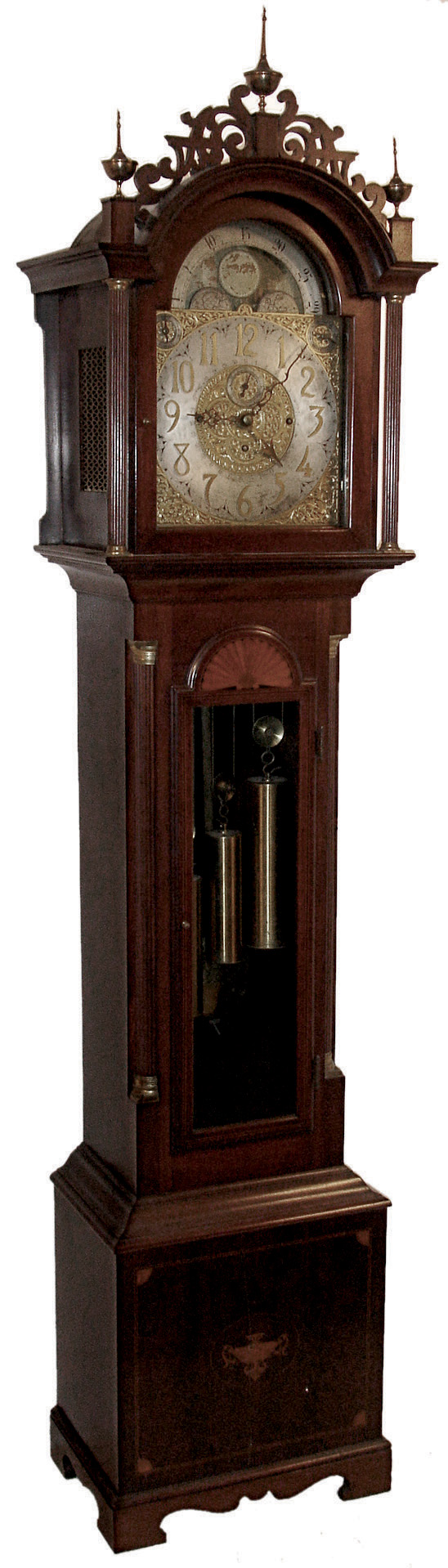 J.J. Elliott, 5 Percival St., London, England, tall case clock, 8 days, time, strike, with calendar and chimes on eight bells and five gongs. Three brass, weight driven movement in a inlaid mahogany case with fluted corner columns with brass capitals. Fretwork crest with three brass finials, inlaid herring bone, fan and urn elements. The brass dial has a silvered chapter ring, engraved and pierced brass spandrels and elaborate dial center, moon phase, subsidiary seconds, strike / silent and tune selectors for Whittington &amp; Westminster, c1915 — Antique Clocks Price Guide