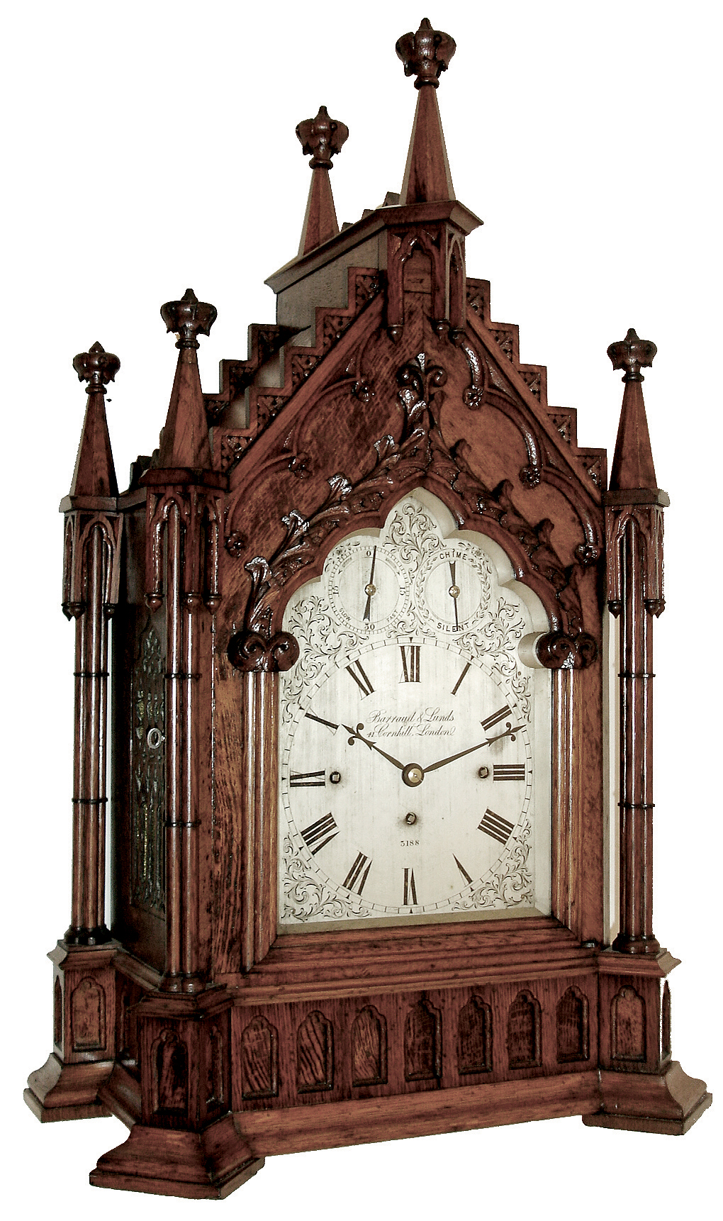Barraud &amp; Lunds, 41 Cornhill, London, large bracket clock in the Gothic style, carved oak case with buttress corners supporting clustered columns, the door also with clustered column style ornament and topped with foliate carving, gables with carved, stepped ornament, case top surmounted by 6 octagonal pinnacles with crockets, case sides with ornately pierced wooden frets, Roman numeral silvered dial with engraved spandrels, blued steel hands, 8 days, 3 train fusee movement, with chiming on eight bells and counting the hours on a large gong, the back plate also signed , c1845 — Antique Clocks Price Guide