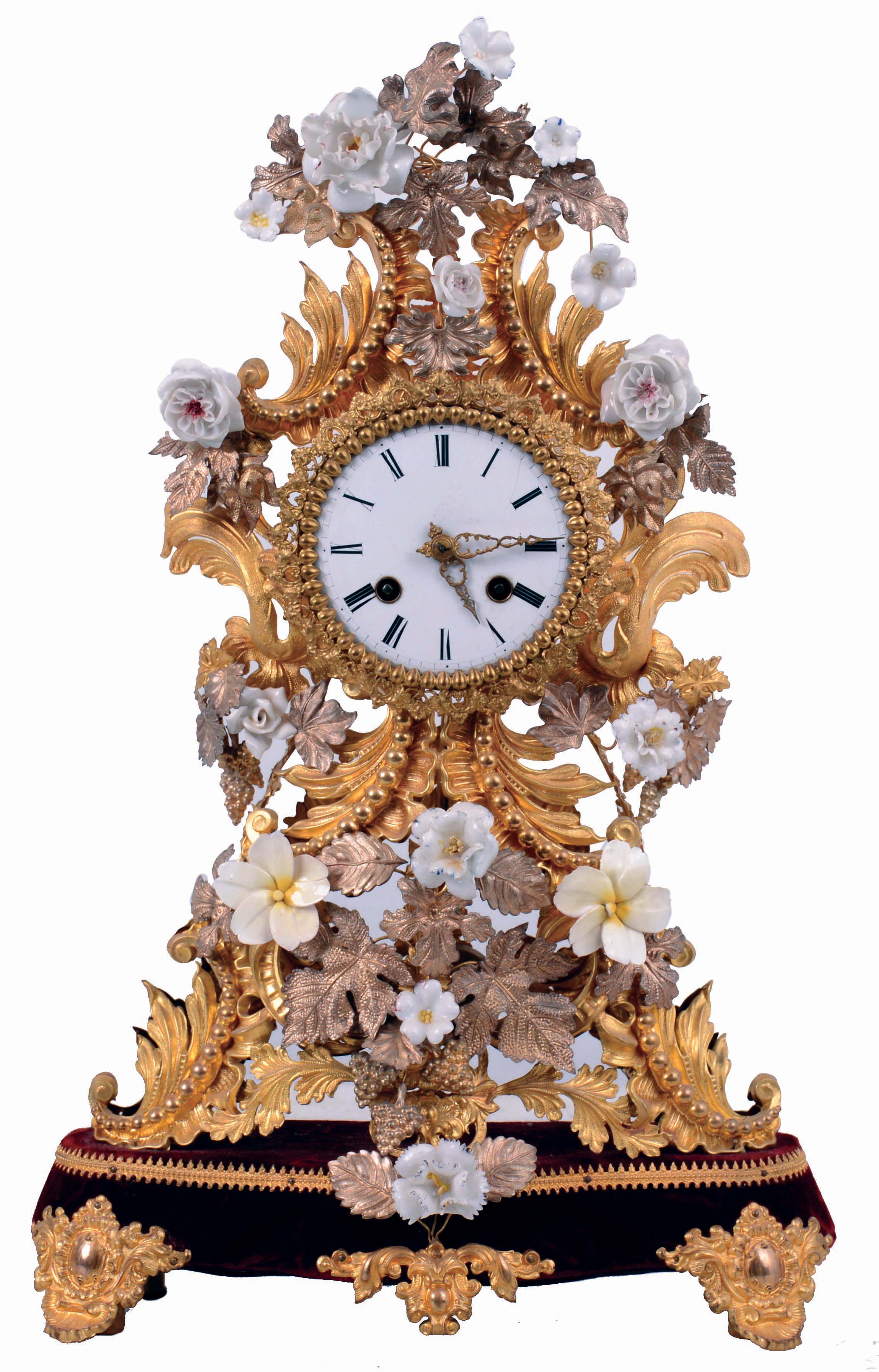 France, decorative mantel clock, the case of gilded and silvered stamped brass foliate elements in the rococo style, and with porcelain flowers, Roman numeral white enamel dial, fancy gilt hands, 8 days pendule a Paris movement with silk thread suspension, striking on a bell, the back plate marked "B &amp; C Paris", mounted to a velvet covered wooden base with gilt feet and central ornament, c1850 — Antique Clocks Price Guide
