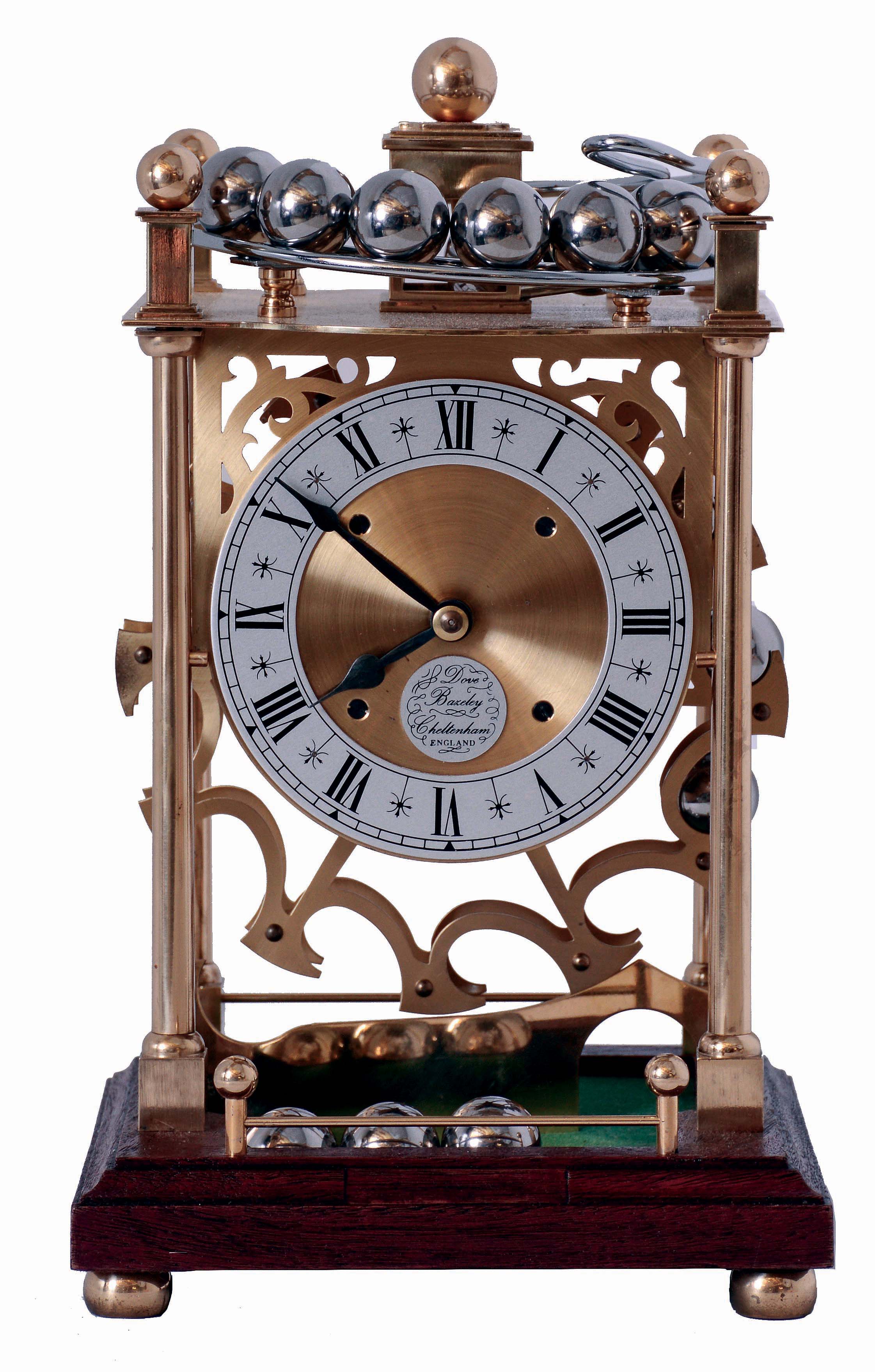 Dove Bazely Ltd., Cheltenham, England, Perpetuum clock, polished brass portico style case with mahogany base, Roman numeral silvered dial, 8 days, timepiece movement powered by a spring, and 24 steel balls, which drop from the rail on the case top onto the "ferris wheel" attached to the winding arbor behind the movement, with paperwork, c1986 — Antique Clocks Price Guide