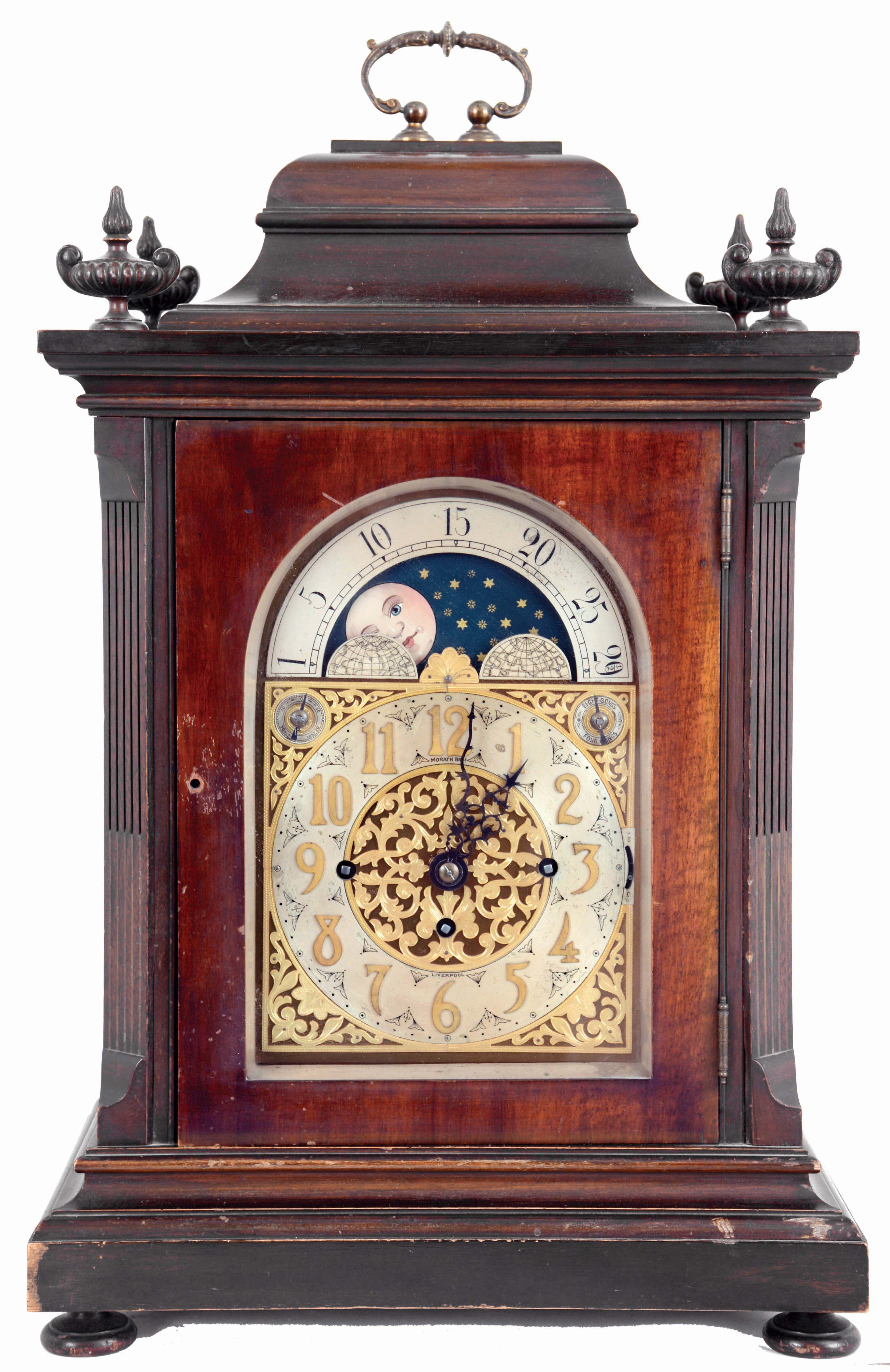 Winterhalder &amp; Hofmeier, Germany, for Morath Brothers, Liverpool, England, 3 train bracket clock. The mahogany case has a heavily molded base and top, stop fluted pilasters and carved urn finials, the doors and sides with thick, beveled glasses, signed composite dial with Arabic numeral silvered chapter ring, gilt spandrels and center, and with moon phase display in the arch, 8 days fusee movement chiming at the quarters on four or eight gongs, and counting the hours on a larger gong. Inside of case is a Morath Brothers label dated July, 1918 — Antique Clocks Price Guide
