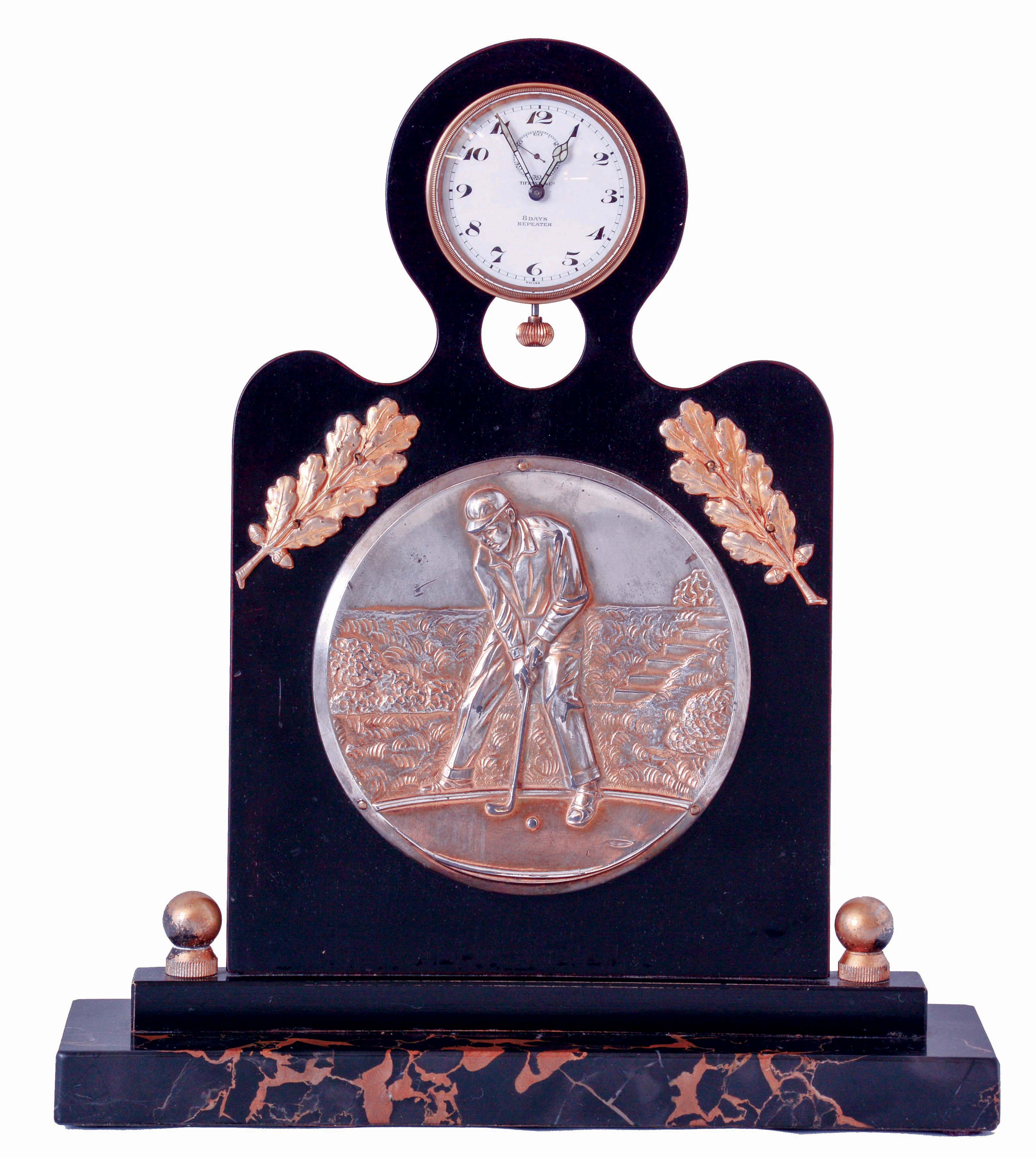 Angelus Watch Co., Switzerland, for Tiffany &amp; Co., New York, golf themed desk clock, portoro marble base supporting an ebonized wood stand, mounted with a silver gilt repoussE plaque depicting a golfer putting, with two applied gilt branches with oak leaves above, and with clock mounted at the top, the 8 days, 15 jewel, minute repeating nickel plate movement with centrifugal governor, lever escapement, and cut bimetallic balance, Arabic numeral white enamel dial, signed "Tiffany &amp; Co., 8 Days Repeater", with blued steel luminous hands, case back dated May 14, 1932 — Antique Clocks Price Guide