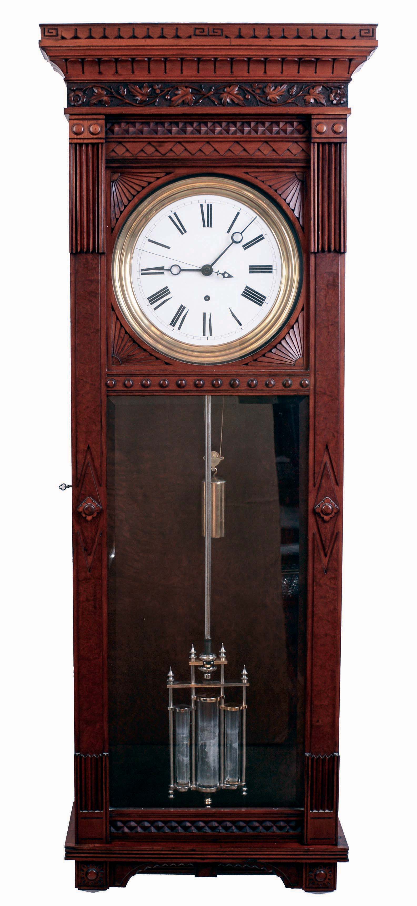 Waterbury Clock Co., Waterbury, Conn (attribution). "Regulator No. 7" variant, jeweler's regulator wall clock, 8 days, time only, weight driven Swiss movement with pinwheel escapement, three jar mercury pendulum and center sweep seconds in a cherry case with detailed carving around top and bottom, backboard and door with burled highlights, fan carved dial surround with a white enamel dial, c1890 — Antique Clocks Price Guide