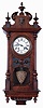 Lenzkirch, Germany, hanging regulator, walnut and walnut veneer case, door with turned columns resting on fluted plinths, and with applied, turned ornament, base with lobed bracket and turned drops, top with turned finials, carved scrolls, fluted plinths, and central female mask, Roman numeral white enamel dial, blued steel hands, pendulum with triangular ball, and repousse ornament in the Jugendstil style, 8 days time and strike movement with ting tang quarters on two gongs, serial #999918, c1895