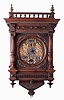 J. Salfer, Wien, large walnut wall clock, the case with turned and carved architectural elements, and with applied brass ornament, bottom with carved bracket, door with applied spandrels, each with a banner inscribed with a short phrase in German, top with balustrade and brass finials, matted brass dial with applied female figures flanking the silvered dial with Roman numeral chapter, and calendar display apertures at 12:00, 5:00 and 7:00, fancy blued steel hands, massive, long running movement with day/ date/ month calendar, and with phases of the moon, with provision for starting the pendulum without opening the case, the main "I" shaped plate with auxiliary strike movement attached at upper left, c1870