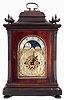Winterhalder & Hofmeier, Germany, for Morath Brothers, Liverpool, England, 3 train bracket clock. The mahogany case has a heavily molded base and top, stop fluted pilasters and carved urn finials, the doors and sides with thick, beveled glasses, signed composite dial with Arabic numeral silvered chapter ring, gilt spandrels and center, and with moon phase display in the arch, 8 days fusee movement chiming at the quarters on four or eight gongs, and counting the hours on a larger gong. Inside of case is a Morath Brothers label dated July, 1918