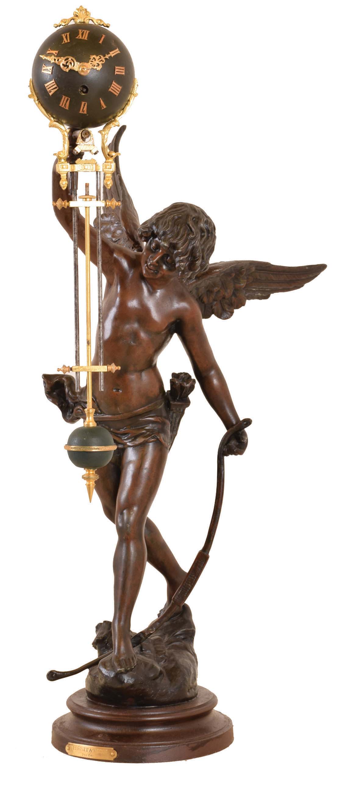 France, swinging clock, titled "Hesitation", by Geo. Maxim, the figure of a young Amor with wings, bow, and quiver, and with his right arm held aloft, and supporting the swinging timepiece, the 8 day movement contained in the patinated, upper sphere, with three rod gridiron style connection to matching lower ball, alll mounted to a painted, molded base — Antique Clocks Price Guide