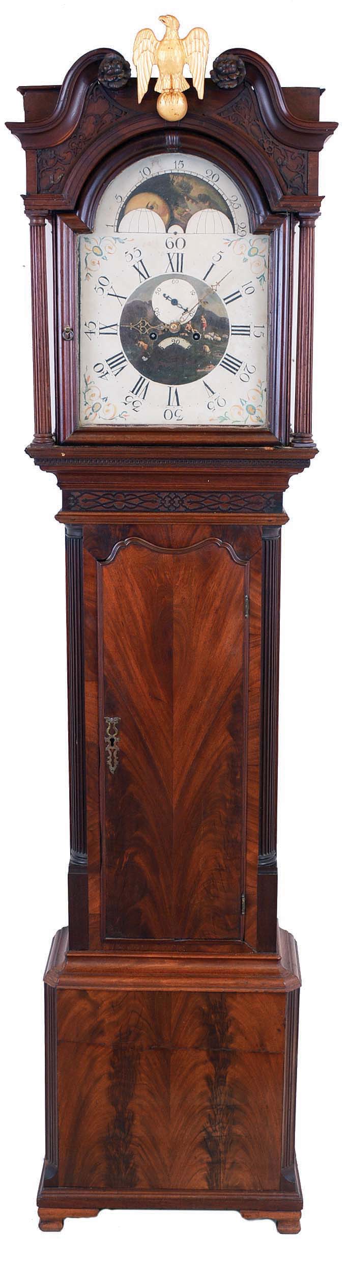 Unsigned, English tall case clock, 8 day, time and bell strike, weight driven movement in a figured mahogany case with Chinese Chippendale decoration on hood below arches and on frieze above trunk door, carved floral rosettes, full round fluted columns flanking dial and matched crotch mahogany veneers on trunk door and base with reeded corners with lamb's tongue stop resting on ogee feet. The painted metal dial has date calendar and moon phase. This style of case was made in the Manchester and Liverpool areas of western England. — Antique Clocks Price Guide