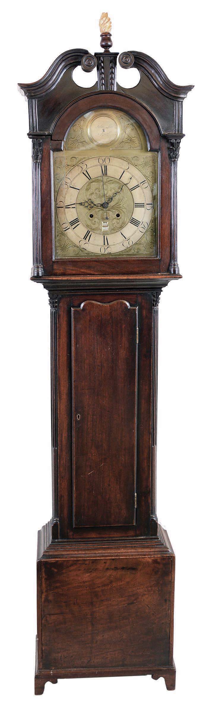 John Law, Beith, (Scotland) tall case clock, 8 day, time, bell strike with calendar, weight driven movement in a mahogany case with broken arch top, fluted rosettes, carved gilded flame finial, fluted corner columns with carved tops flanking hood over a trunk with contoured door top, flanked by top fluted corner columns with carved tops on a base with straight bracket feet. The brass engraved dial has a silvered chapter ring, engraved spandrels and dial center, calendar aperture at 6, sweep second's and signature boss. The unusual calendar mechanism displays both date and month, with specialized marking to indicate 30 or 31 days, in two apertures. — Antique Clocks Price Guide