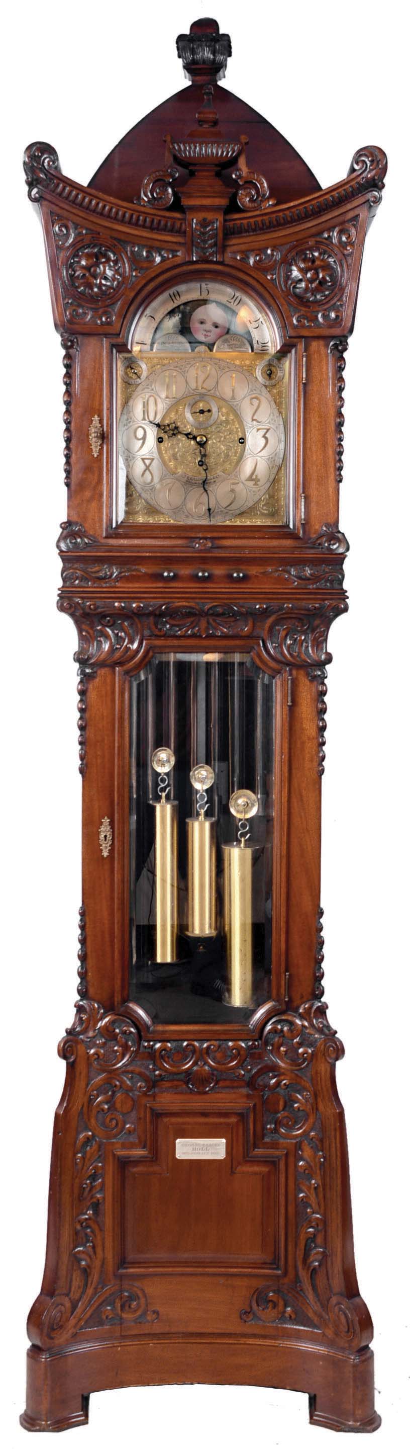 Walter H. Durfee, Providence, Rhode Island, for J.E. Caldwell &amp; Co., Philadelphia, Penn. on dial, 8 tube hall clock, 8 days, time, strike and quarter chimes. three weight driven, damascened movement. Plays Westminster or tunes on "Bow Bells". Tubes signed by Walter Durfee with patent dates 1892 &amp; 1896. The case is carved mahogany with an ornately carved pagoda shaped hood with carved urn finial above dial, bent pyramid top surmounted by a square carved finial at apex. The trunk and hood doors have matching brass escutcheons and beveled glass. The carved curve base resting on bracket feet has a retailer panel with presentation plaque to "GEORGE &amp; LAURA HOLL 1873. JUNE 25TH. 1895". The brass dial has moon phase, engraved spandrels and dial center, silvered chapter ring, strike / silent and tune selector discs. [Note: George Holl, Jr. (1840-1915) and Laura Stockton (1851-1920) were married June 25, 1873 at Camden, NJ and lived the rest of their life there. This clock was a 22nd. anniversary gift.] — Antique Clocks Price Guide
