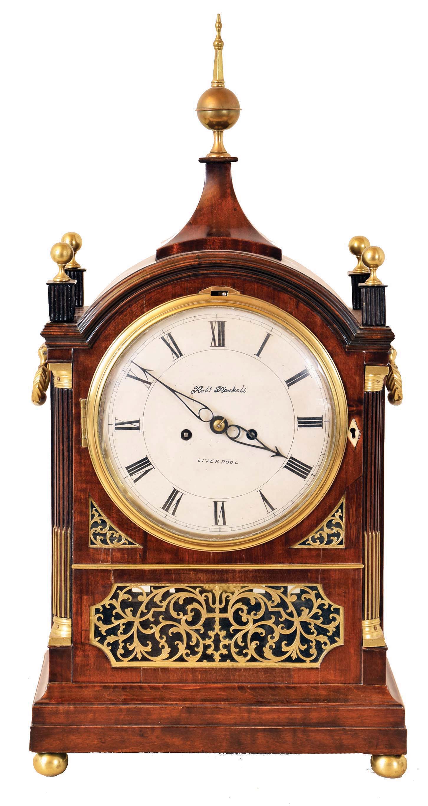 English bracket clock signed, Robert Roskell, Liverpool on the dial, 8 days, time and bell strike, spring driven movement with two fusees in a mahogany veneer Regency period Gothic style case with pierce brass fretwork and inlay and four brass pineapple finials and a painted enamel dial with strike / silent lever above 12 and including a matching shelf. — Antique Clocks Price Guide