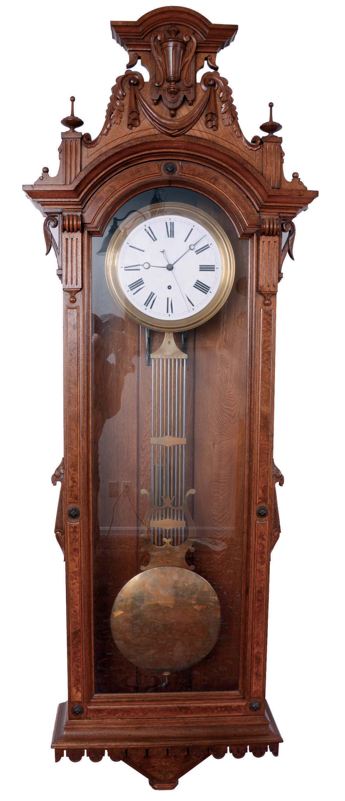 F. Kroeber &amp; Co., New York, N.Y., "Regulator No. 27", jeweler's regulator wall clock, 8 day, time only, brass weight driven with Swiss pinwheel escapement timepiece movement, with a white enameled dial, a gridiron lyre pendulum and sweep seconds in a walnut case with burled accents and ornately carved top showcasing an urn in the center. — Antique Clocks Price Guide