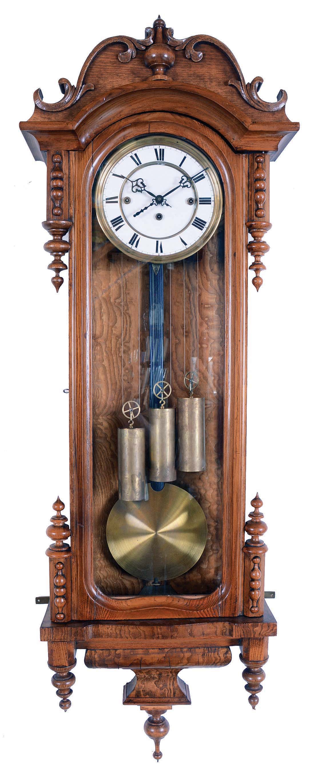 Germany, Vienna regulator wall clock, 8 day, time and Grand Sonnerie, three weight driven movement in an oak case with burled highlights and sides carved top and four spires topped by finials flanking door and three lower finials. The two part white enamel dial has Roman numerals. — Antique Clocks Price Guide