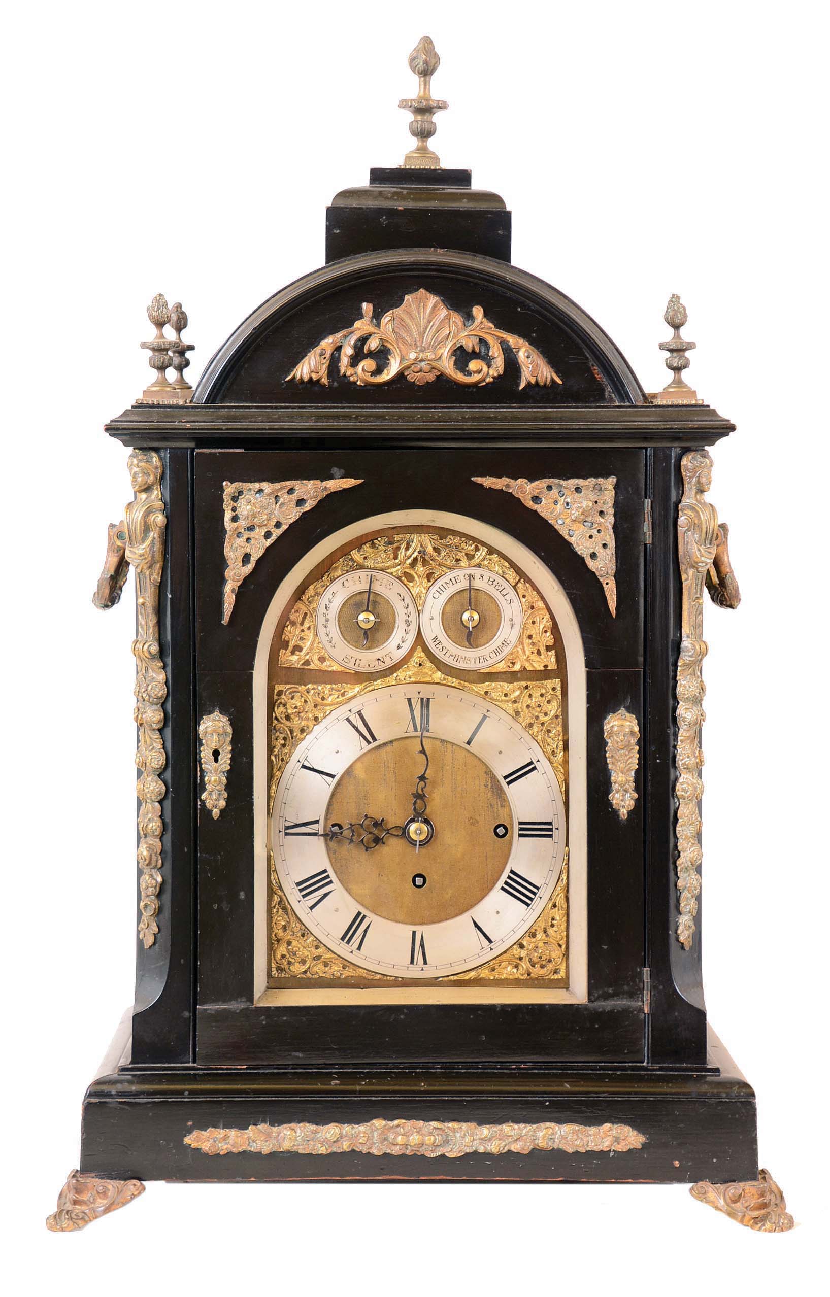 Unsigned, England, large bracket clock, ebonized case with caryatid corners, cast ornaments and feet, the sides with cast, pierced fabric backed frets below foliate ornamented carrying handles, and the top with five finials, composite dial with silvered Roman numeral chapter ring, matted center, gilt spandrels, and the arch with silvered chime select and chime/ silent rings, large three train fusee movement, chiming Westminster on Eight Bells at the quarters, and counting the hours on a large gong — Antique Clocks Price Guide