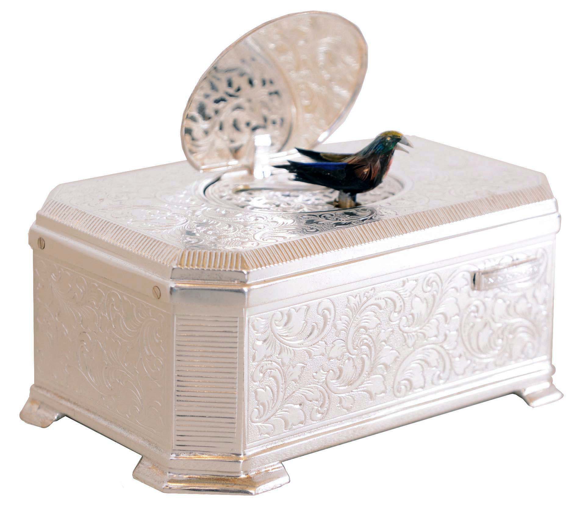 Karl Griesbaum, Germany, singing bird box, silver plated case with leaf and scroll engraving and canted corners, the oval cover engraved with two birds, and opening to reveal the multicolored, singing bird when the slide on the case front is pushed, 20th century — Antique Clocks Price Guide