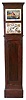 Germany, Black Forest, organ tall clock, 8 days, time and strike, weight driven wooden and brass movement playing 8 tunes through 28 pipes in a mahogany finished soft wood case with two tiered painted wooden dial, the lower section has flower and fruit painted spandrels and the upper section has a painted scene with a castle, bridge, river and boat and is signed by F. Hofmeier of Neustadt.