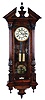 Germany, Vienna regulator wall clock, 8 days, time and strike, brass weight driven movement in a carved architectural walnut case with book matched veneers and cream enamel dial.