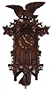 Emilian Wehrle, Germany, hanging Trompeteruhren, or Trumpeter Clock, walnut case with rustic carving, vines and leaves, the top with a large carved eagle, and the bottom also with rustic ornament, the trumpeter concealed behind plank doors, below the turned wooden dial with applied Roman numerals and carved bone hands, the bellows, wind chest, and pipes mounted above the two train, 30 hour movement with pierced brass plates, carved pendulum, and cast iron weights
