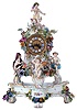 Lenzkirch, Germany, porcelain mantel clock on porcelain stand by Meissen, 8 days, time and strike, spring driven movement in a highly elaborate and delicate polychrome porcelain Meissen case decorated with several putti, floral and foliate elements resting on matching Meissen porcelain stand. The fancy cast brass dial is set with twelve blue Roman numeral cartouches, serial #1110301
