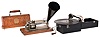 Two (2) phonographs. (1) American Graph phone Co., New York, NY. "BX" model 2-minute wax cylinder phonograph sold by the Columbia Phonograph Co. with reproduction black cone horn. (2) KOMPAConn., phonograph made by the PLA/A Music Co., New York, NY with interior horn.