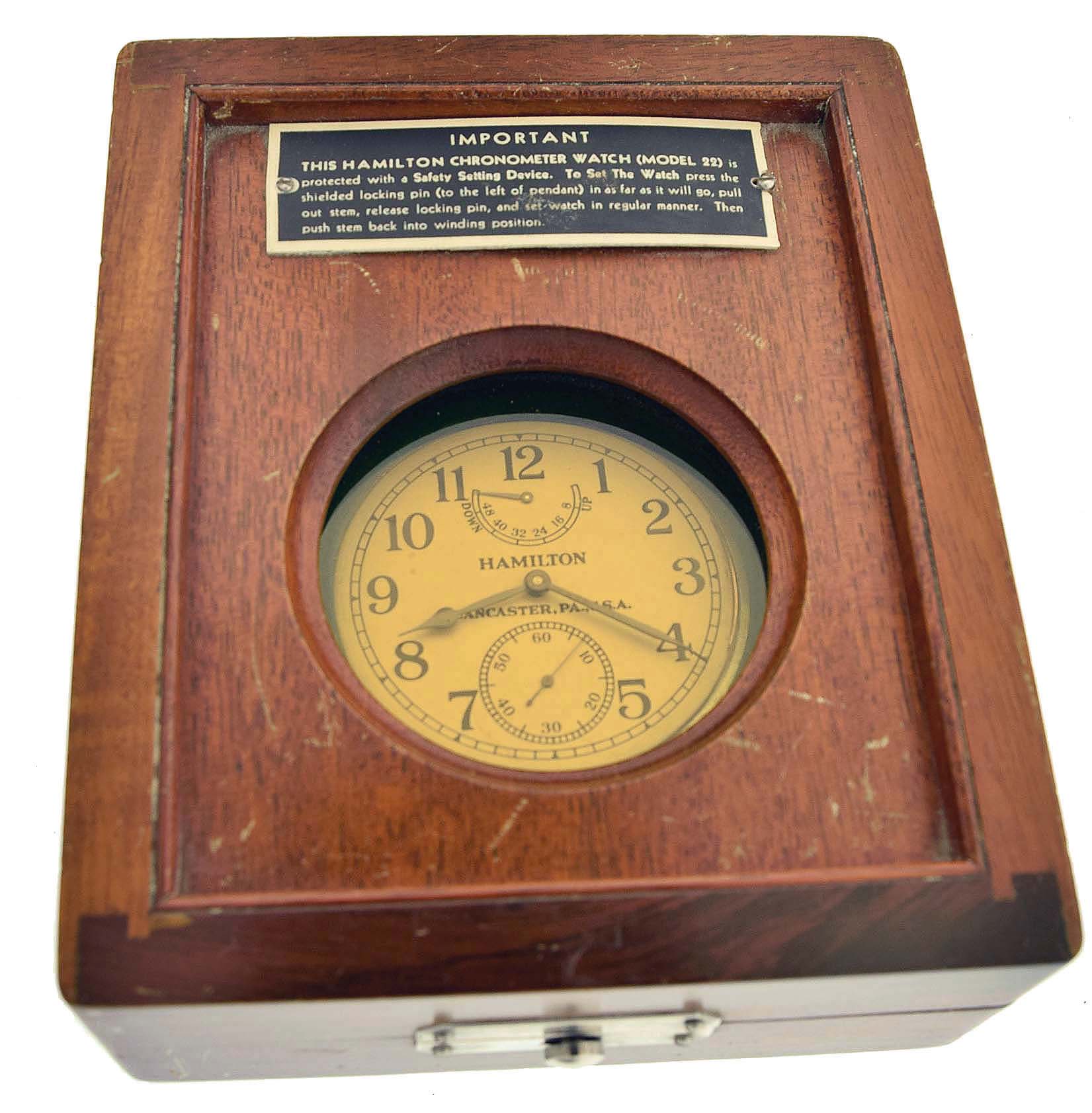Hamilton Watch Co., Lancaster, Penn., model 22 chronometer with wind indicator, 35 size, 21 jewels, stem wind, pin / stem set, adjusted to 6 positions and temperature, straight line damascened nickel plate movement, with lever escapement and micrometric regulator, Arabic numeral metal dial and black steel, spade and poker hands, in a screw back and bezel, open face base metal case with ordnance department information engraved on back, and protective box, with glazed aperture for viewing the timepiece, serial #2F5901. — Antique Clocks Price Guide