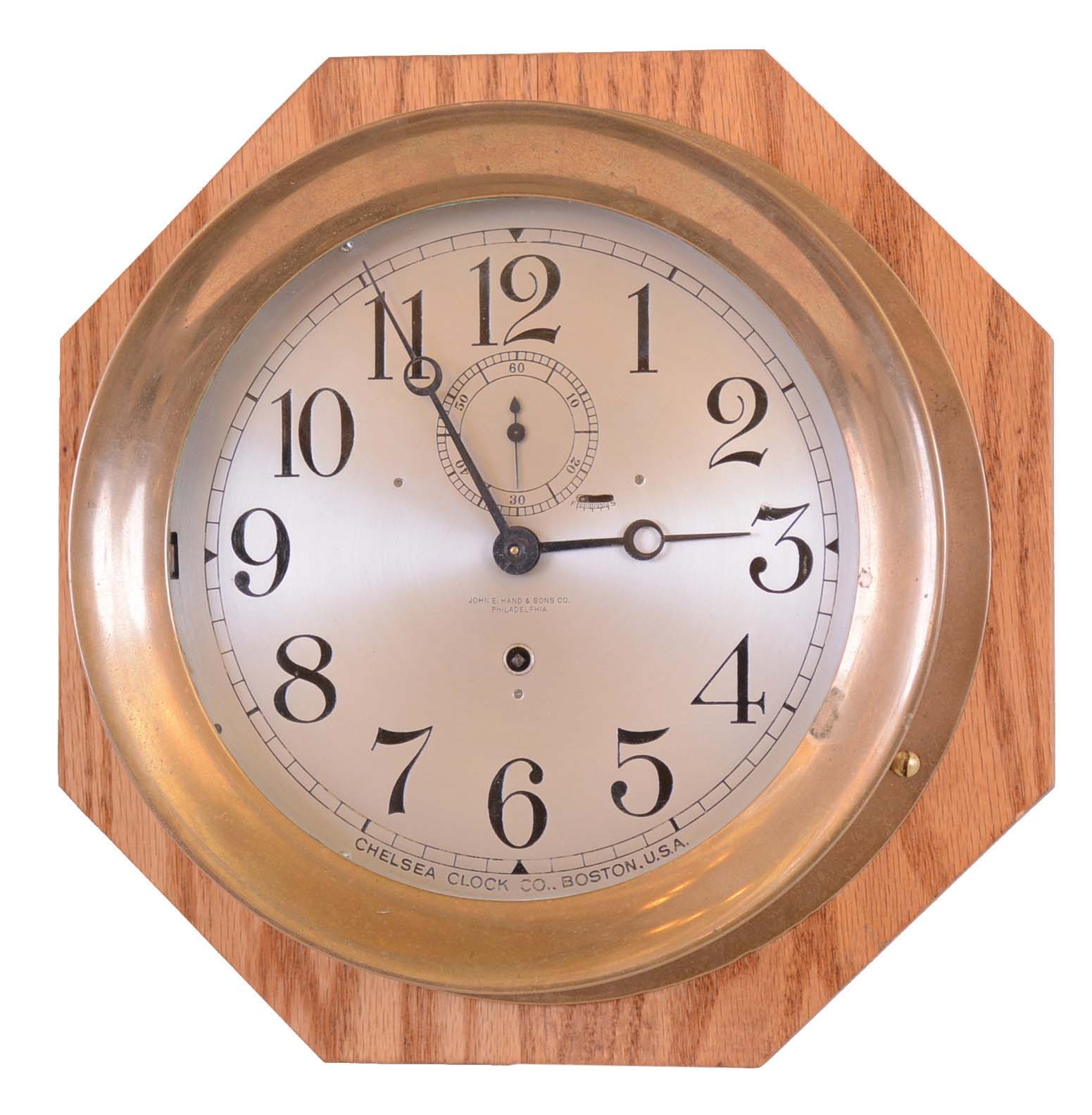 Chelsea Clock Co., Boston, Mass., for John E. Hand &amp; Sons, Co., Philadelphia, brass case hinged bezel 8" dial time only engine room clock, #165517 shown in Demeter book as completed 4 / 29 / 25, mounted on newer octagonal oak board — Antique Clocks Price Guide