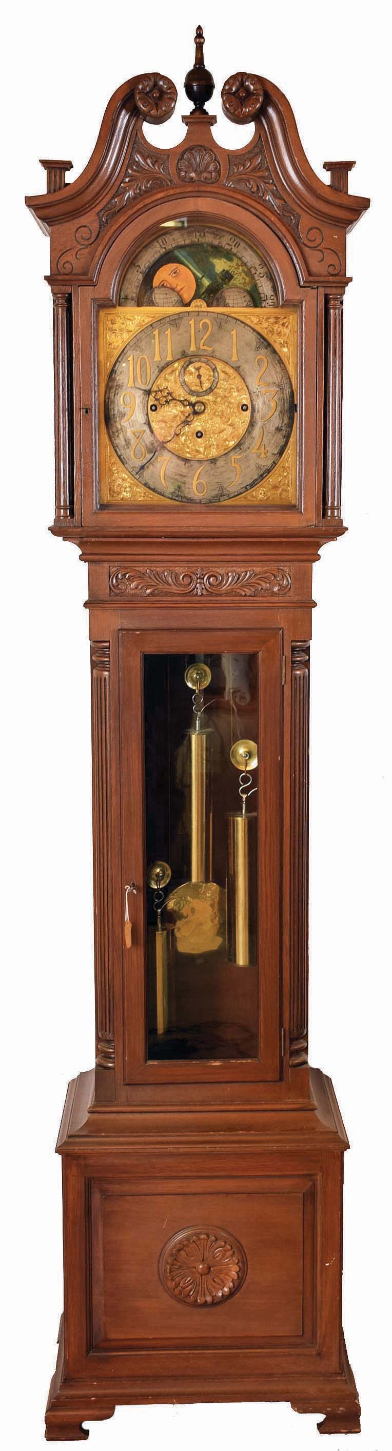 J.J. Elliot, London, England, tall clock, 8 days, time, strike and chiming on gongs, three brass weight driven movement signed Elliot in an oak case with broken arch on hood flanked by full columns, carved rosettes, glazed trunk door, reeded quarter columns and ogee feet. The brass dial has silvered chapter ring and moon phase. — Antique Clocks Price Guide