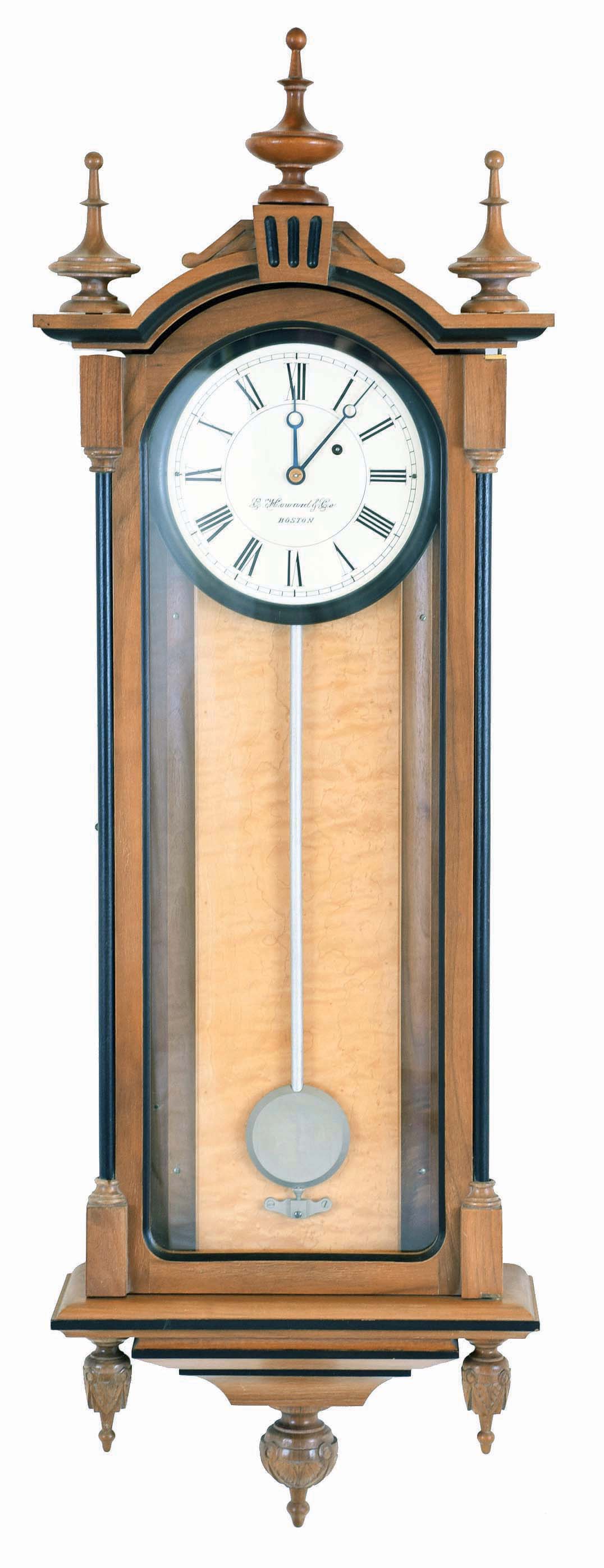 E. Howard &amp; Co., Boston, Mass., "No. 59- 8 Regulator" reissue. Walnut case with ebonized moldings, turned and carved finials, curly maple weight baffle, ebonized wooden bezel with Roman numeral white painted 8" dial, blued steel moon hands, nickel pendulum with silver painted wooden rod, 8 day weight driven timepiece movement, The clock has serial number 275 on the movement and the case and is dated October, 1976. — Antique Clocks Price Guide