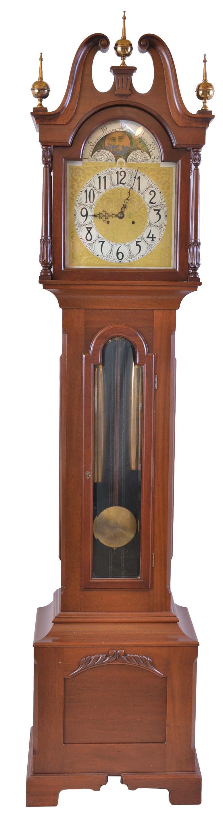 New Haven Clock Co., New Haven, Conn., "Sherbrooke" variant tall clock, 8 day, time, strike and Westminster chime on gongs, three brass weight driven ladder chain movement with Wilcox patent signed subsidiary movement to drive chimes in a mahogany case with broken arch top, four full carved columns on hood, beveled glass trunk door, bracket base and feet. The silvered brass dial has moon. — Antique Clocks Price Guide