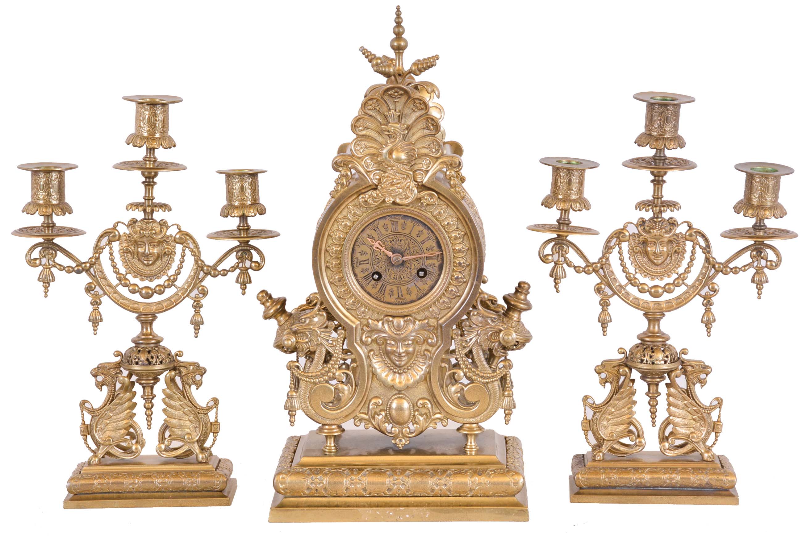 Lenzkirch, Germany, a three piece mantel garniture, ornate cast case with gryphons, masks, and a riot of indescribable ornament, with a pair of three arm candelabra similarly decorated, Roman numeral brass dial, 8 day time and strike movement, serial #414911 — Antique Clocks Price Guide