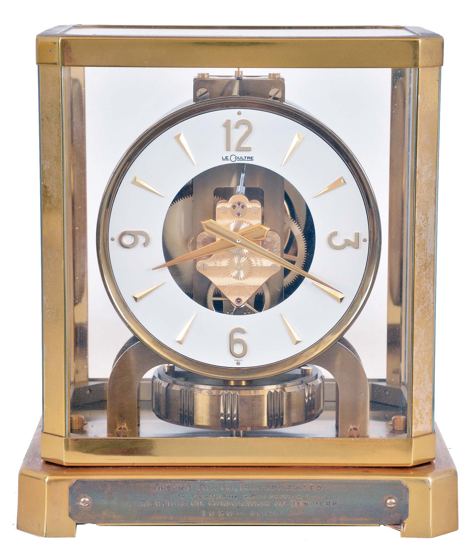 LeCoultre &amp; Cie, Switzerland, "Atmos" clock, 15 jewel gilt caliber 528 movement, gilt torsion pendulum, round white painted dial with applied gilt Arabic numerals and arrow markers, gilt hands, all contained in a glazed rectangular case with removable top, presentation plaque mounted to front of base, with Atmos pamphlet, serial #123665 — Antique Clocks Price Guide